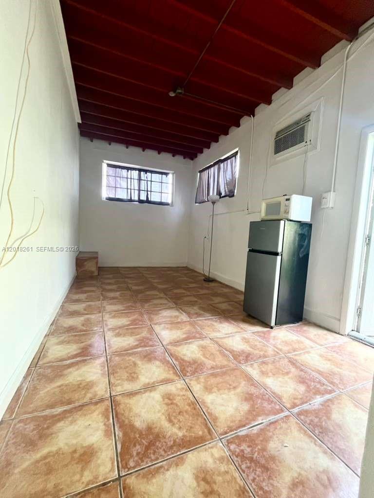 A narrow room features tiled floors, a red-painted exposed beam ceiling, and a small refrigerator — 1875 NE 177th St # 0, North Miami Beach FL 33162, NORTH MIAMI BEACH, FL