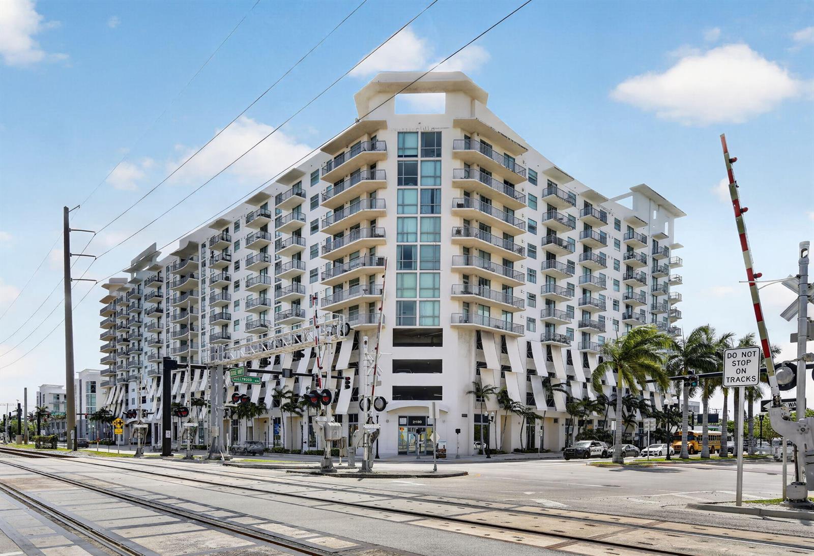 A multi-story apartment building stands next to railroad tracks with a crossing signal — 140 S Dixie Highway # 819, Hollywood FL 33020, HOLLYWOOD, FL