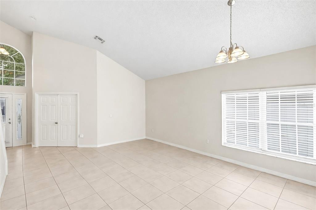 An empty room with light tile floors, a vaulted ceiling, and a chandelier — 7946 GOLDEN POND CIRCLE, KISSIMMEE, FL
