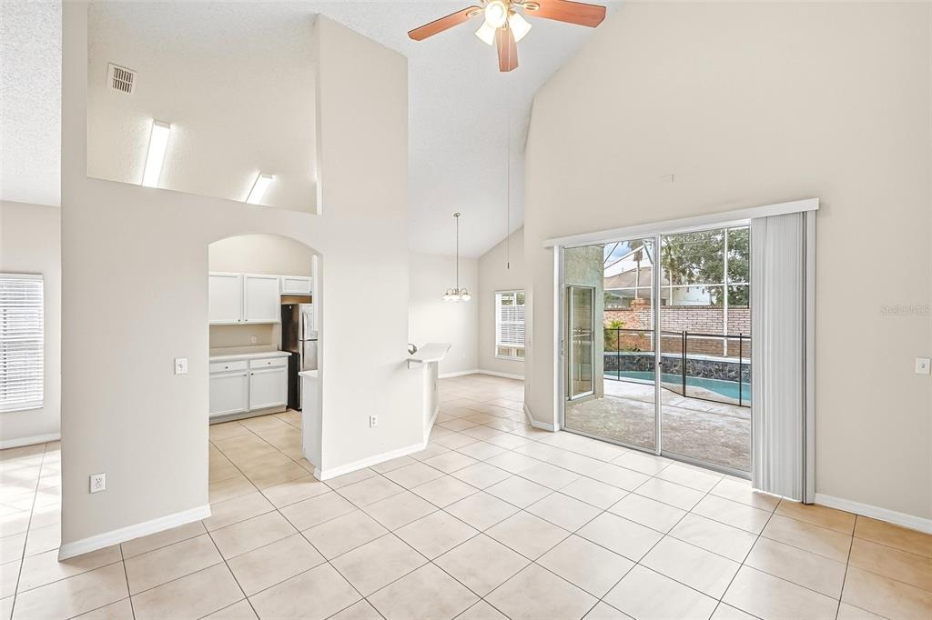 A bright living area with tile floors, vaulted ceilings, and a sliding door to a pool — 7946 GOLDEN POND CIRCLE, KISSIMMEE, FL