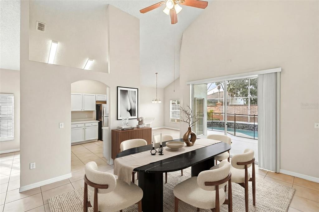 A dining room with a dark oval table, cream chairs, and a view of a pool — 7946 GOLDEN POND CIRCLE, KISSIMMEE, FL