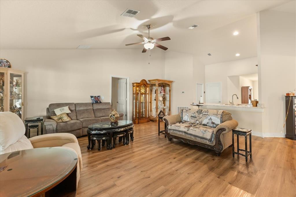 A living room features light wood-look flooring, a ceiling fan, and two sofas — 906 EDITH DRIVE, FRUITLAND PARK, FL