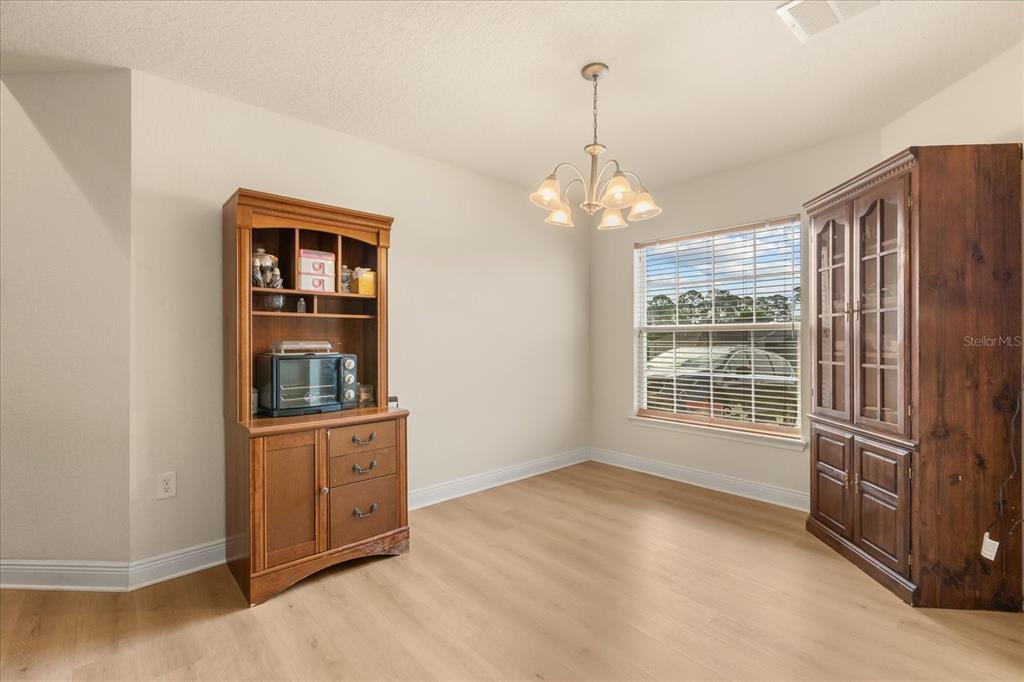 A dining room features light wood flooring, a chandelier, and two large wooden cabinets — 906 EDITH DRIVE, FRUITLAND PARK, FL