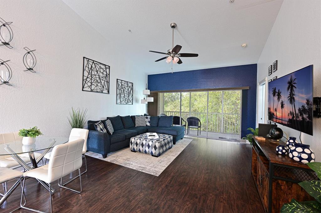 A living room features a blue sectional sofa, a dining area, and a balcony view — 6589 FAIRWAY GARDENS DRIVE UNIT 202, BRADENTON, FL