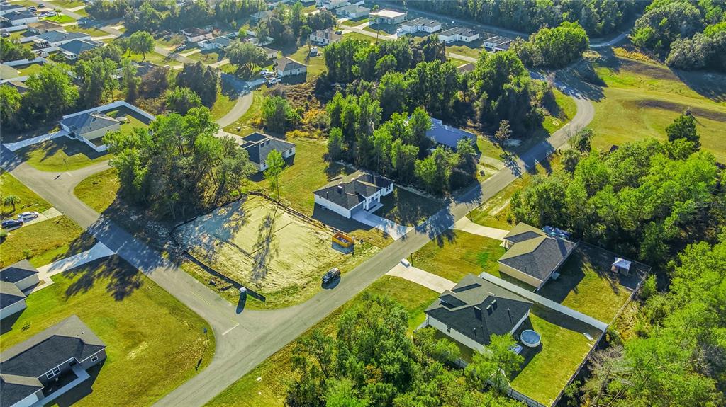 An aerial view shows a suburban neighborhood with houses, wooded areas, and a vacant lot — 13690 SW 43RD CIRCLE, OCALA, FL