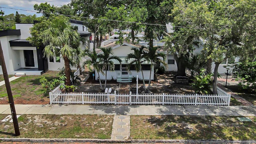 A white house with a front porch and palm trees sits behind a white picket fence — 3829 2ND AVENUE N, ST PETERSBURG, FL
