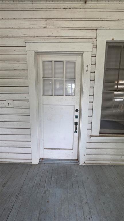 A white wooden door with a six-pane window sits on a porch with horizontal siding — 918 E LIME STREET UNIT 1, LAKELAND, FL