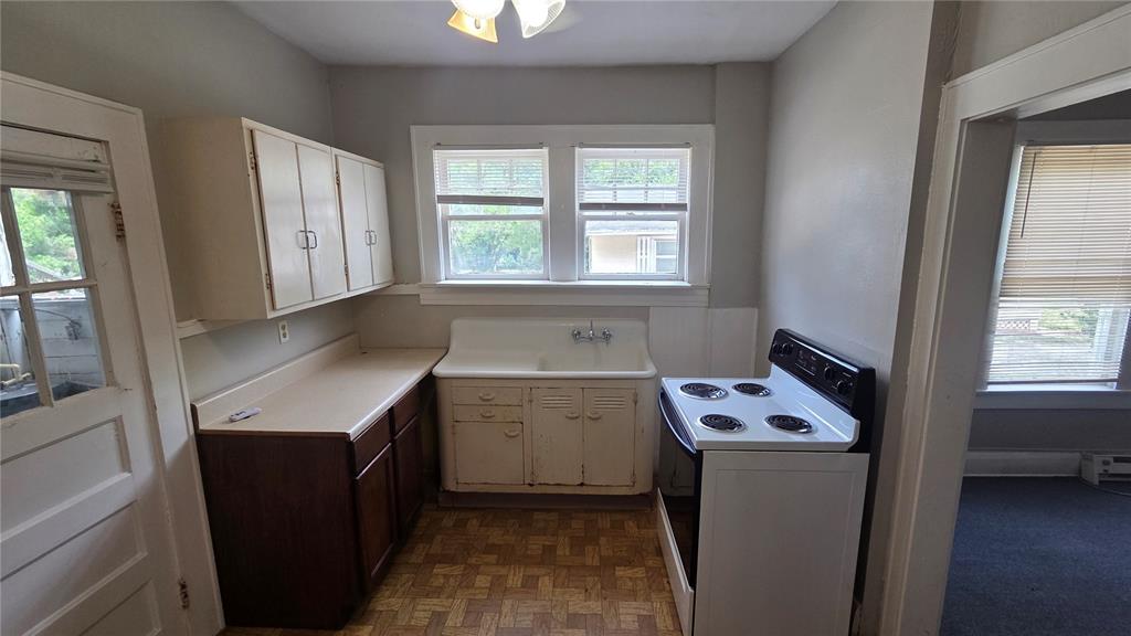 A kitchen features a white sink, dark wood cabinets, a white stove, and linoleum flooring — 918 E LIME STREET UNIT 1, LAKELAND, FL