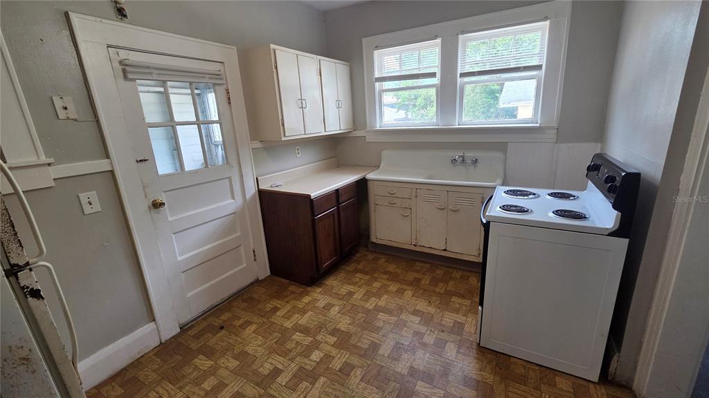 A kitchen features a white stove, a vintage sink, wooden cabinets, and patterned vinyl flooring — 918 E LIME STREET UNIT 1, LAKELAND, FL