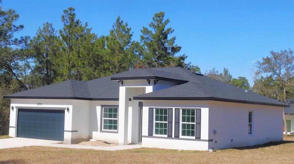 A single-story house with a white stucco exterior, dark roof, and a two-car garage — 3717 W MALBY LANE, CITRUS SPRINGS, FL