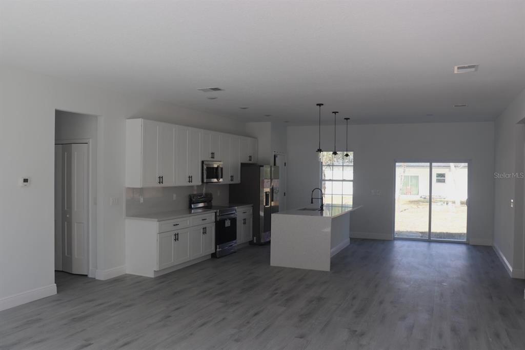 A modern kitchen features white cabinets, stainless steel appliances, a center island, and gray flooring — 3717 W MALBY LANE, CITRUS SPRINGS, FL