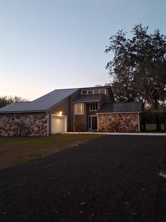 A two-story house with a metal roof, stone facade, and an attached garage — 2598 ENTERPRISE OSTEEN ROAD, OSTEEN, FL