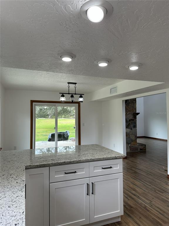A kitchen island with white cabinets and granite countertops sits before a sliding glass door — 2598 ENTERPRISE OSTEEN ROAD, OSTEEN, FL