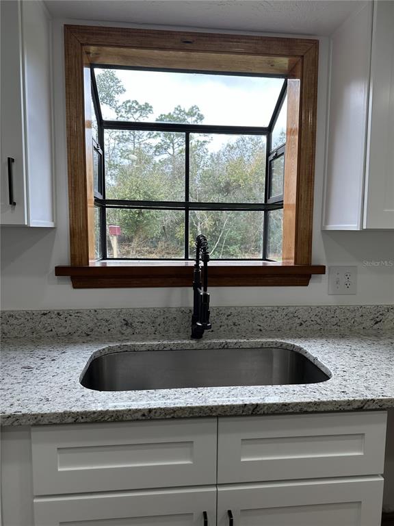 A kitchen sink with a dark faucet is positioned beneath a window with wood trim — 2598 ENTERPRISE OSTEEN ROAD, OSTEEN, FL