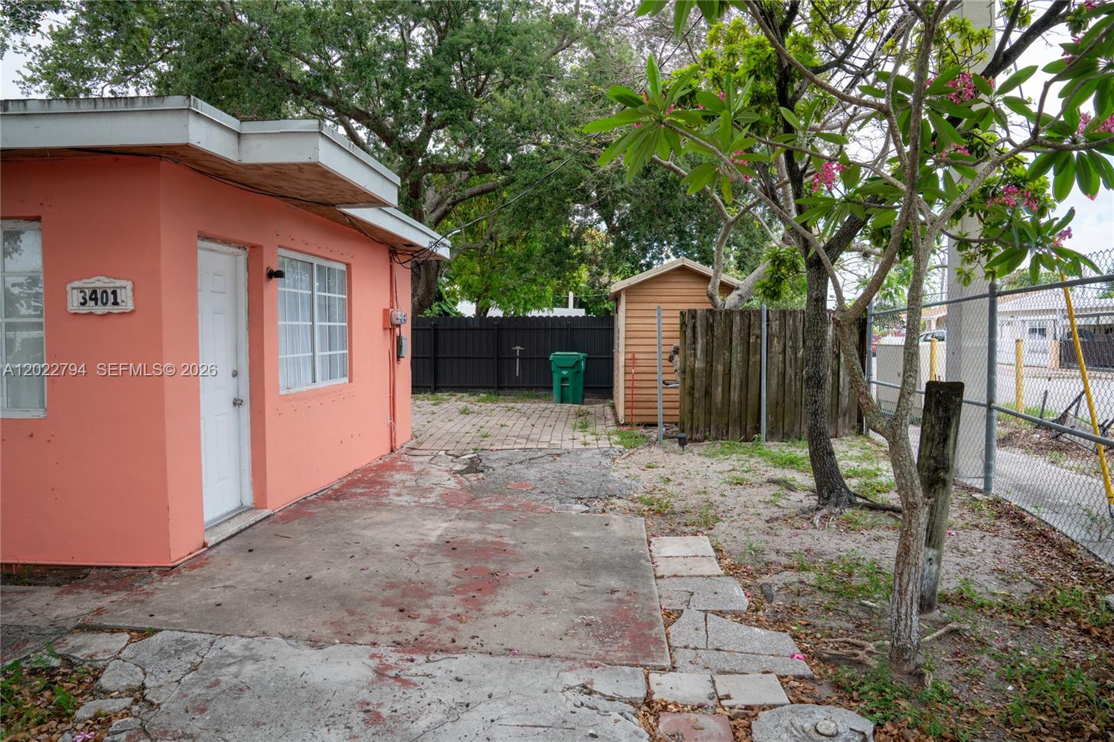 A peach-colored building exterior features a concrete patio, a small shed, and a fenced yard — 3401 NW 15th St, Miami FL 33125, MIAMI, FL