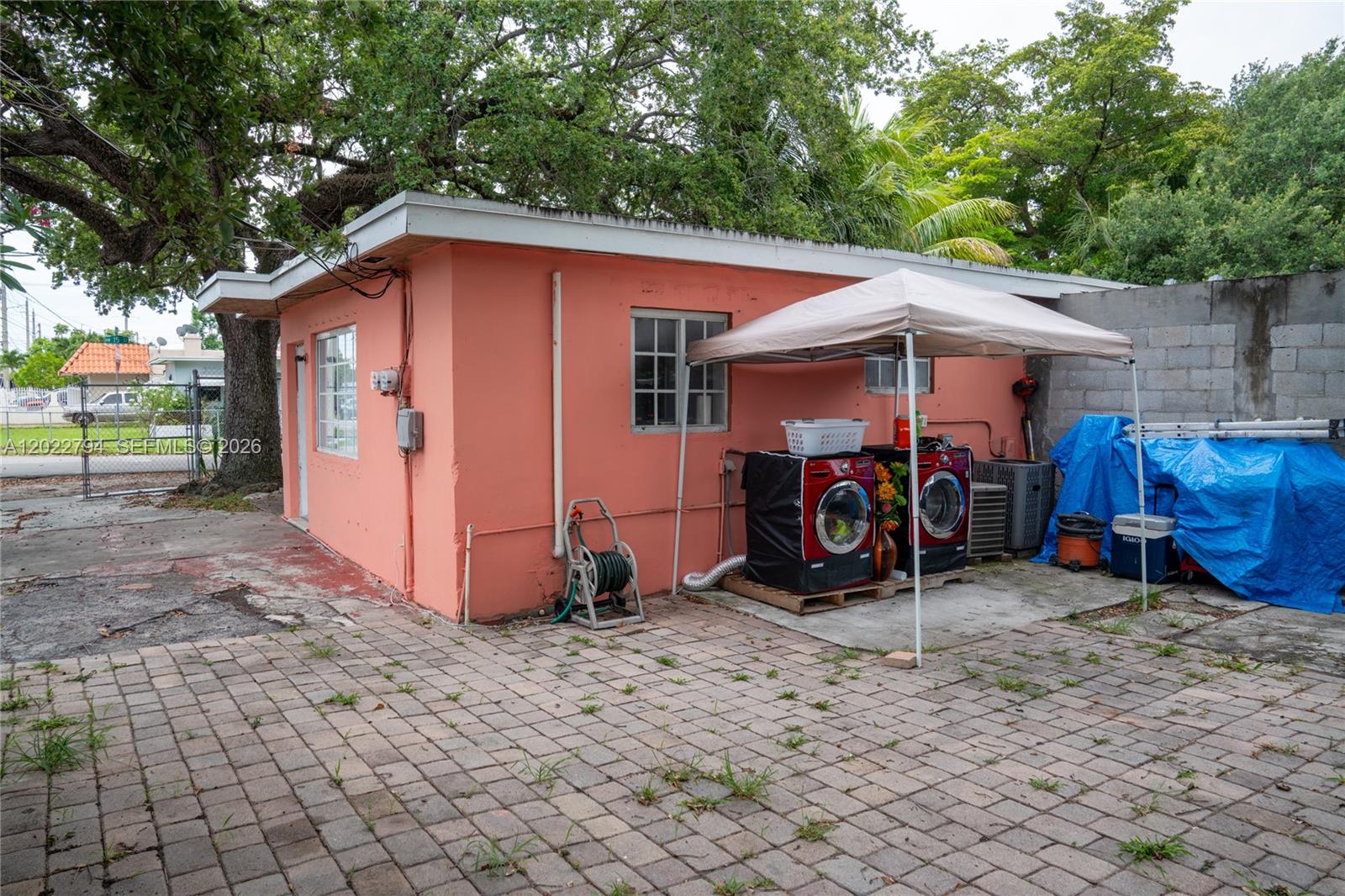 An exterior view of a peach-colored building with outdoor laundry appliances under a canopy — 3401 NW 15th St, Miami FL 33125, MIAMI, FL