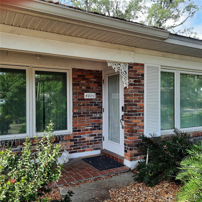 The exterior of a house features a brick facade, a white front door, and windows — 4806 W SAN JOSE STREET, TAMPA, FL