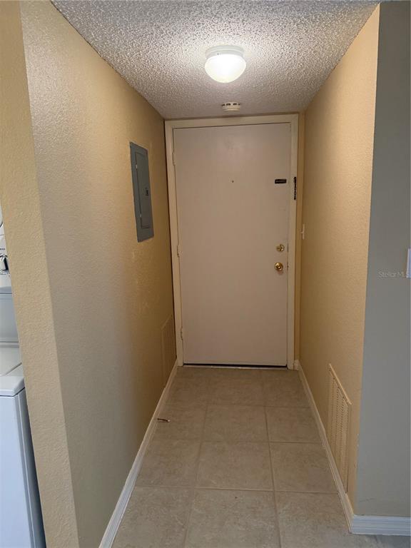 An entryway features a white door, tiled floor, a ceiling light, and a wall-mounted electrical panel — 3586 CAPE HAZE DRIVE UNIT B6, ROTONDA WEST, FL