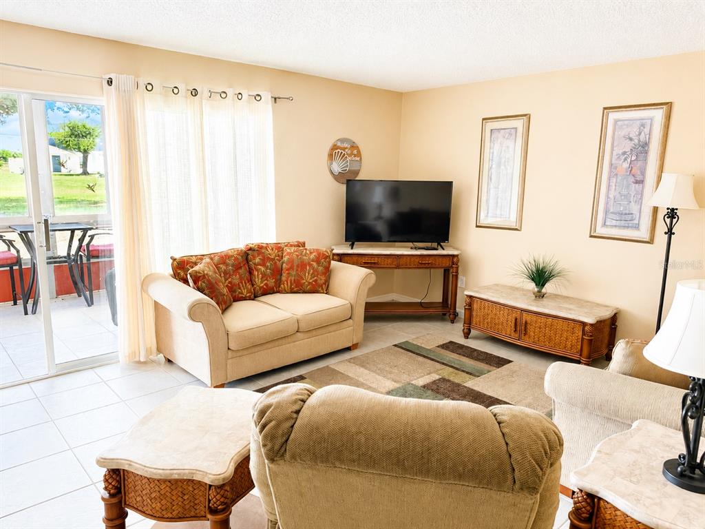 A living room features a beige sofa, a television on a console, and tile flooring — 3586 CAPE HAZE DRIVE UNIT B6, ROTONDA WEST, FL