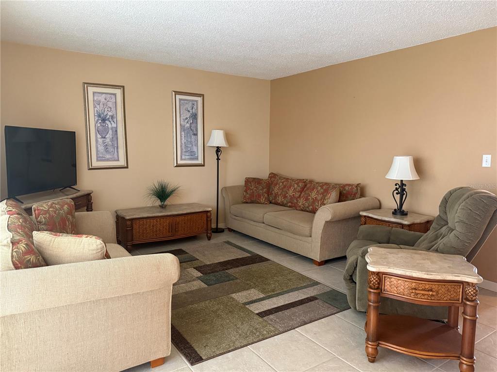 A living room features two beige sofas, a green recliner, and a geometric area rug — 3586 CAPE HAZE DRIVE UNIT B6, ROTONDA WEST, FL