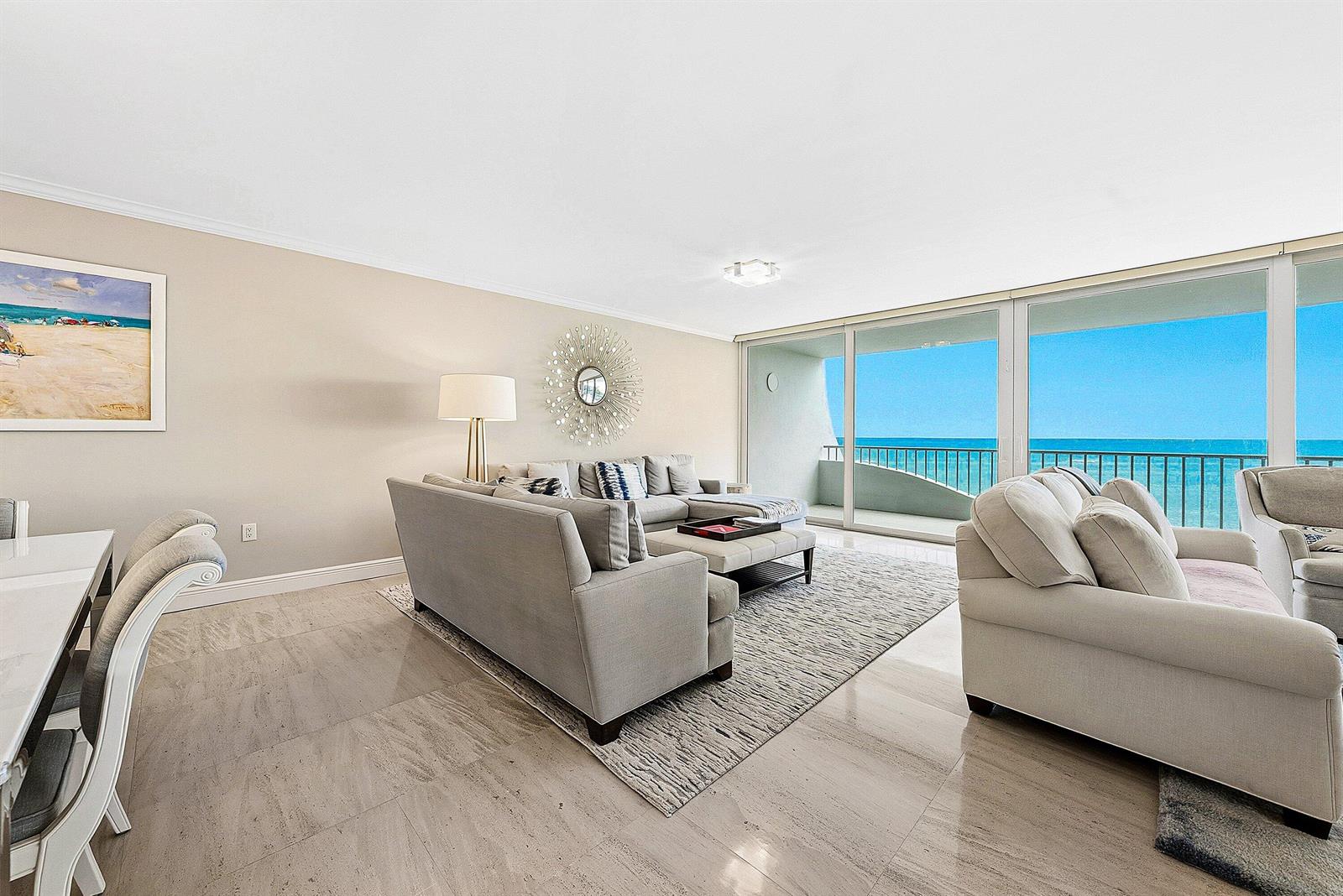 A living room features light tile floors, a gray sectional sofa, and floor-to-ceiling ocean views — 2001 SE Sailfish Point Boulevard # 313, Stuart FL 34996, STUART, FL