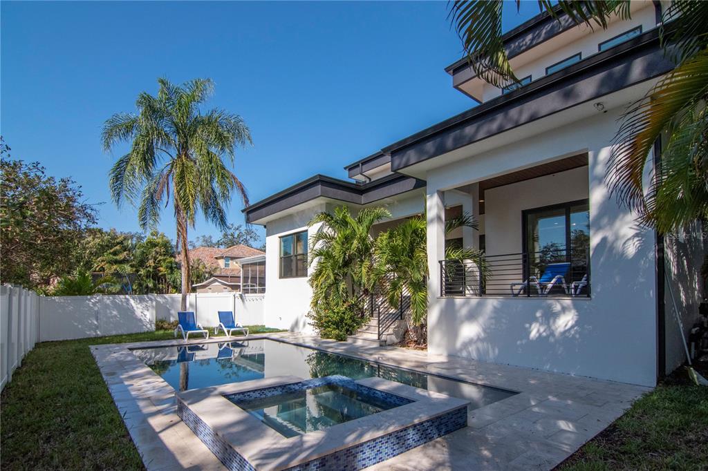 A backyard features a swimming pool with an attached spa, lounge chairs, and a modern house — 4604 W LOWELL AVENUE, TAMPA, FL