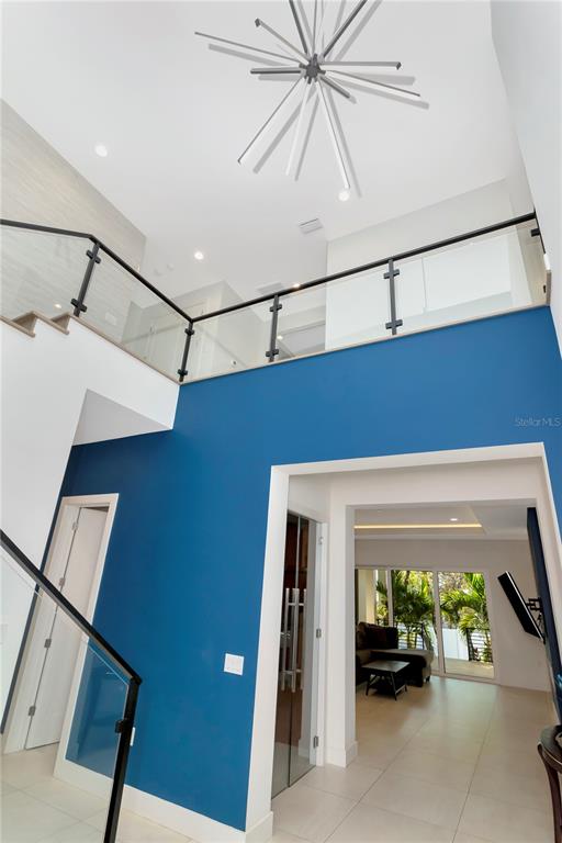 A two-story foyer features a blue accent wall, glass railings, and a modern sputnik chandelier — 4604 W LOWELL AVENUE, TAMPA, FL