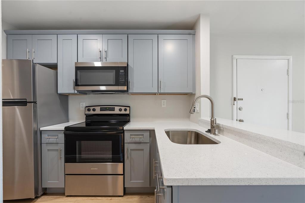 A kitchen features gray cabinets, stainless steel appliances, and white countertops with a breakfast bar — 3848 N LAKE DRIVE UNIT 138, TAMPA, FL