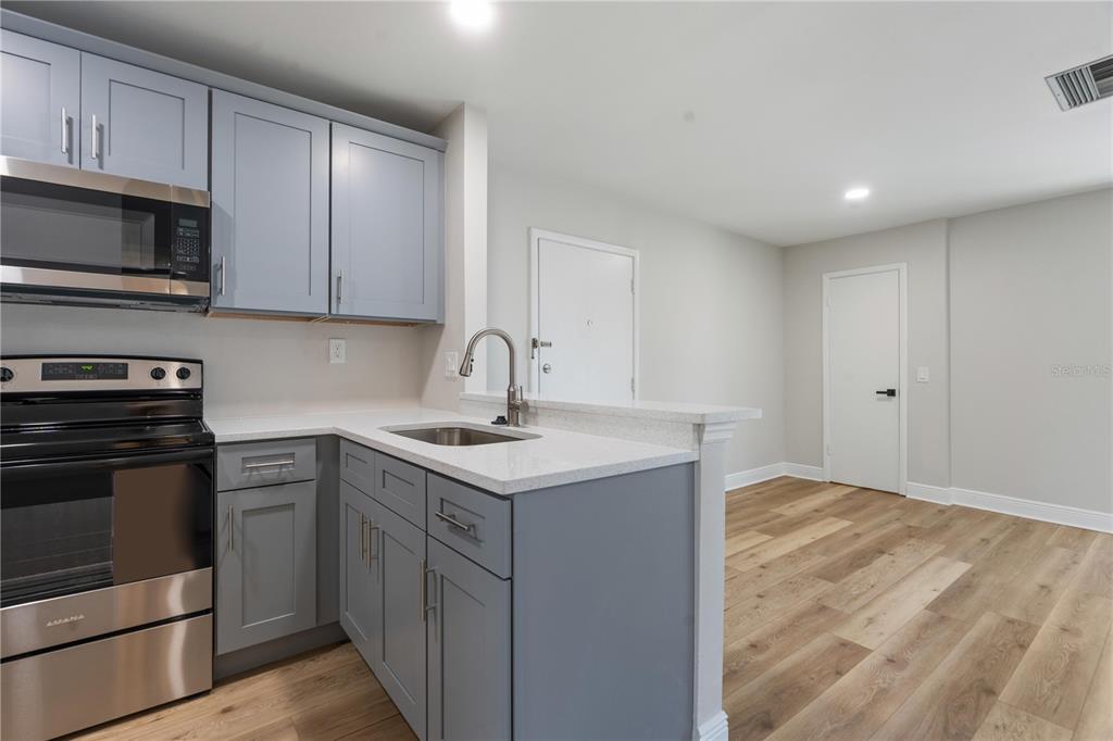 A kitchen with gray cabinets, stainless steel appliances, and light wood flooring — 3848 N LAKE DRIVE UNIT 138, TAMPA, FL