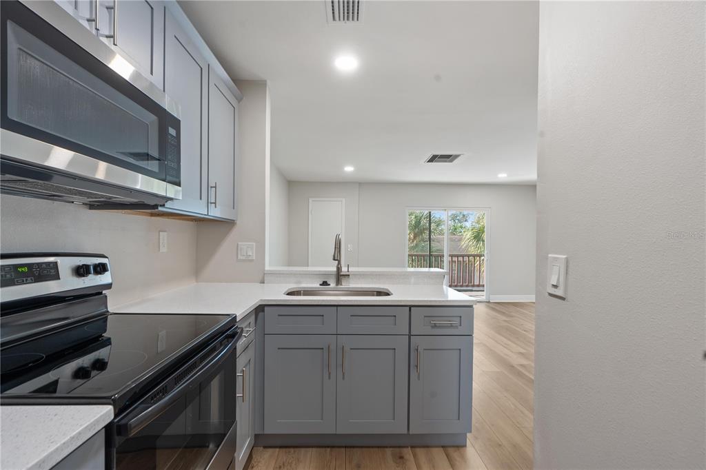 A kitchen with gray cabinets and white countertops overlooks an open living area — 3848 N LAKE DRIVE UNIT 138, TAMPA, FL