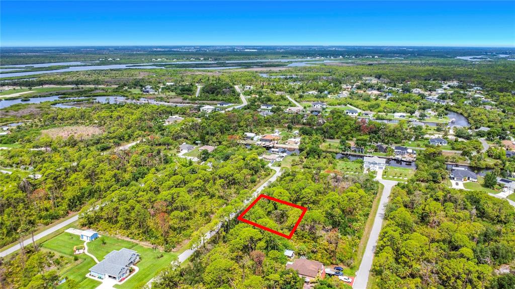 An aerial view shows a vacant, wooded lot outlined in red within a residential neighborhood — 12278 TOYNBEE LANE, PORT CHARLOTTE, FL