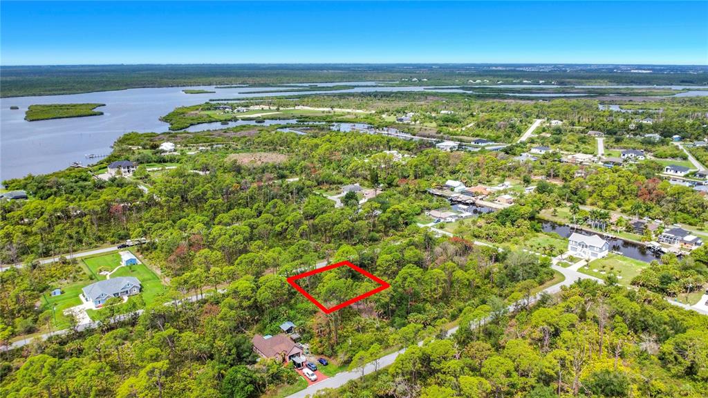 An aerial view shows a rectangular plot of land outlined in red amidst wooded surroundings — 12278 TOYNBEE LANE, PORT CHARLOTTE, FL