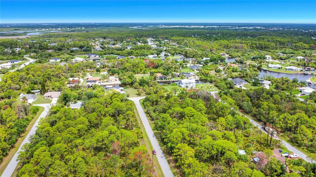 An aerial view shows a residential neighborhood with houses nestled among dense green trees — 12278 TOYNBEE LANE, PORT CHARLOTTE, FL
