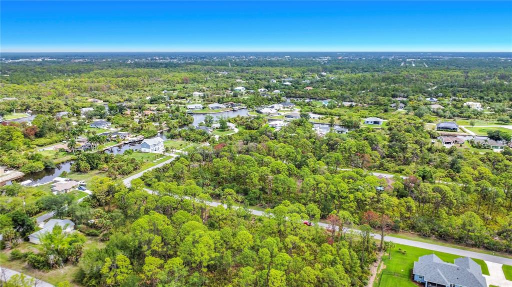 An aerial view shows a residential neighborhood with houses surrounded by dense green trees — 12278 TOYNBEE LANE, PORT CHARLOTTE, FL