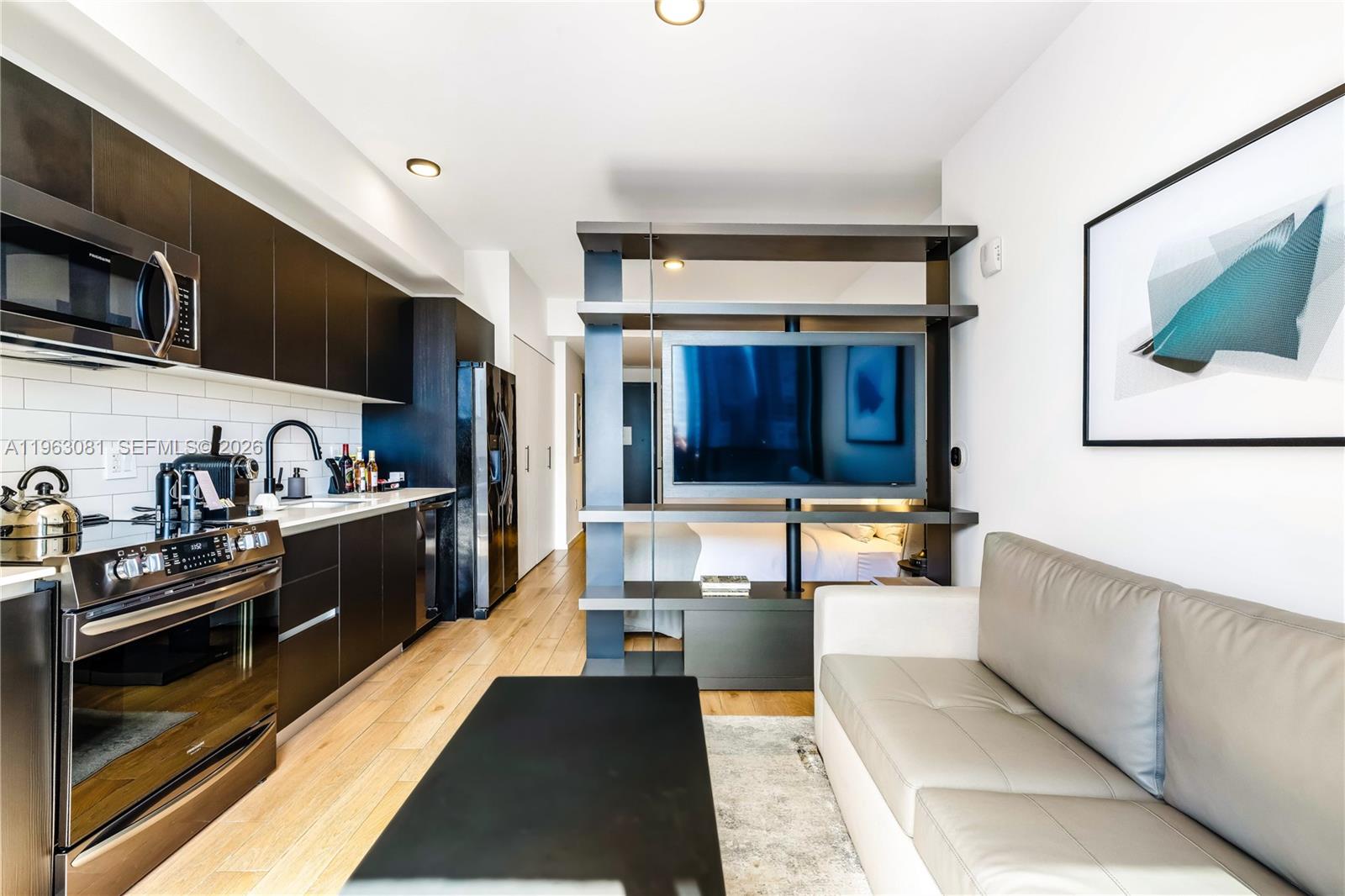 A modern studio apartment features a kitchen, a living area, and a central shelving unit — 398 NE 5th St # 2116, Miami FL 33132, MIAMI, FL