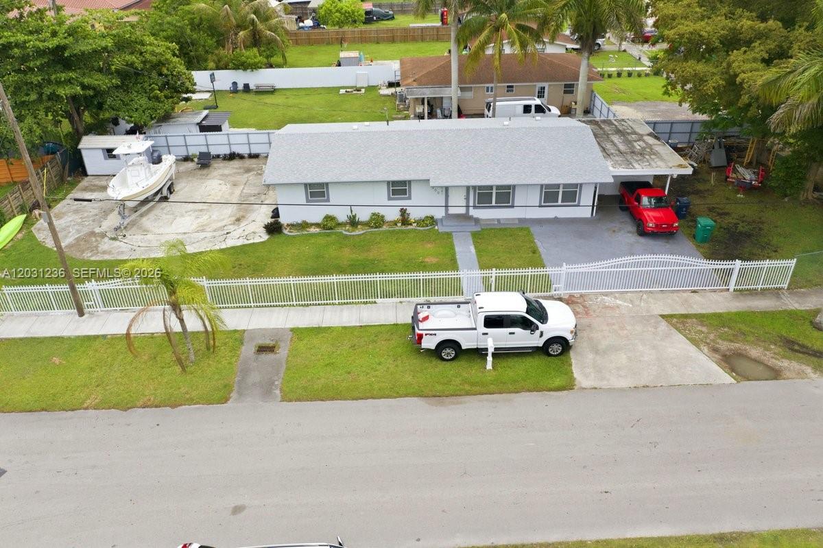 An aerial view shows a single-story house with a white fence, boat, and parked vehicles — 300 SW 8th Ave, Florida City FL 33034, FLORIDA CITY, FL