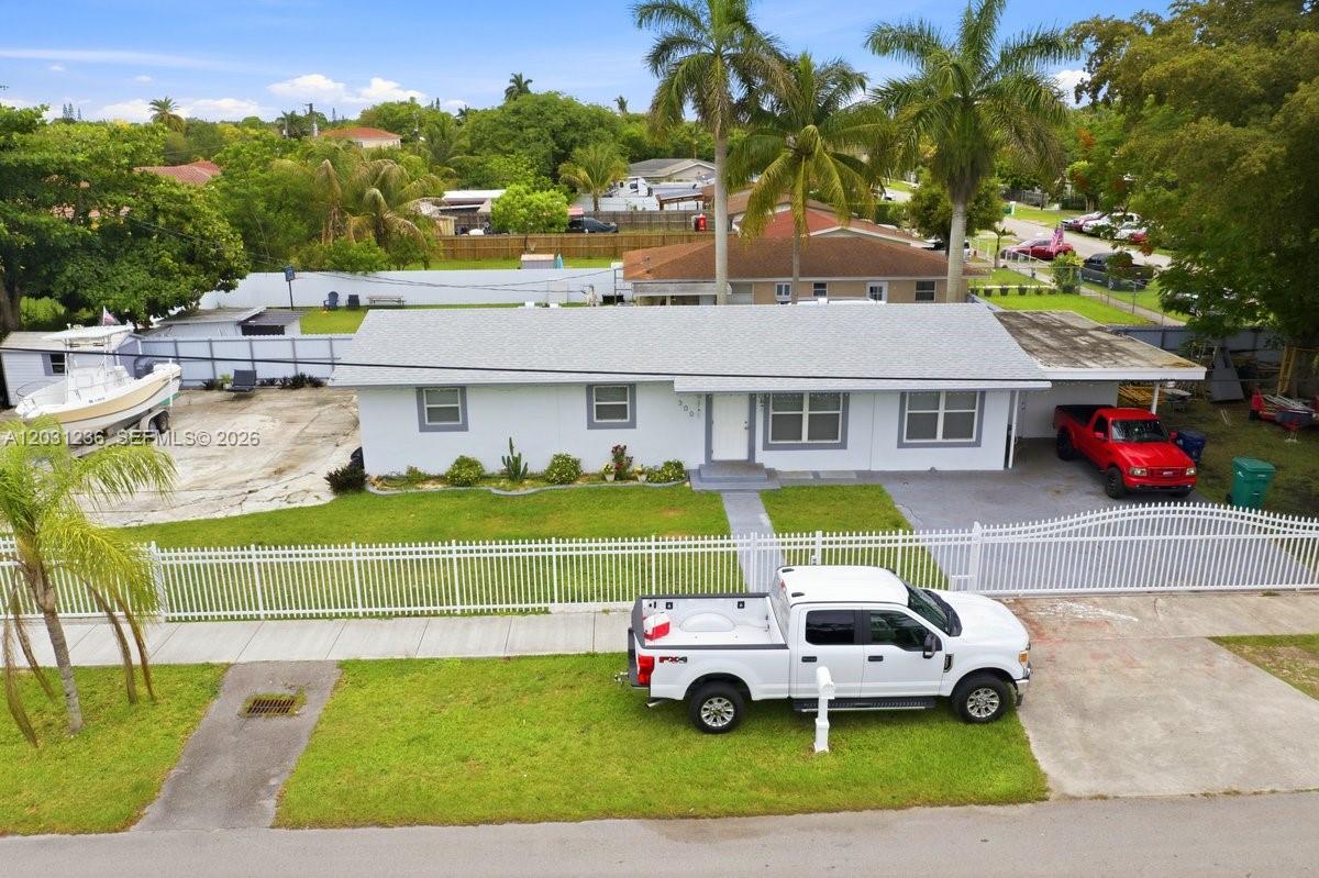 An aerial view shows a single-story house with a white fence and two parked trucks — 300 SW 8th Ave, Florida City FL 33034, FLORIDA CITY, FL