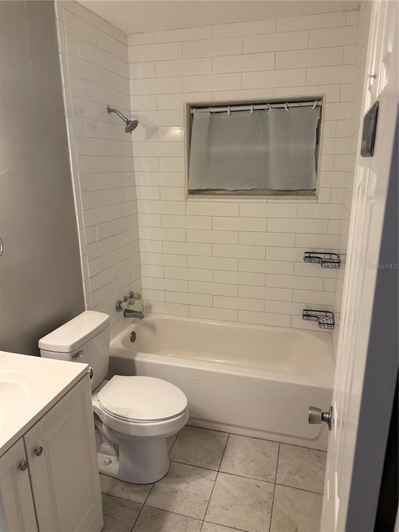 A bathroom featuring a white vanity, toilet, and a bathtub with white subway tile walls — 500 E 25TH STREET, SANFORD, FL
