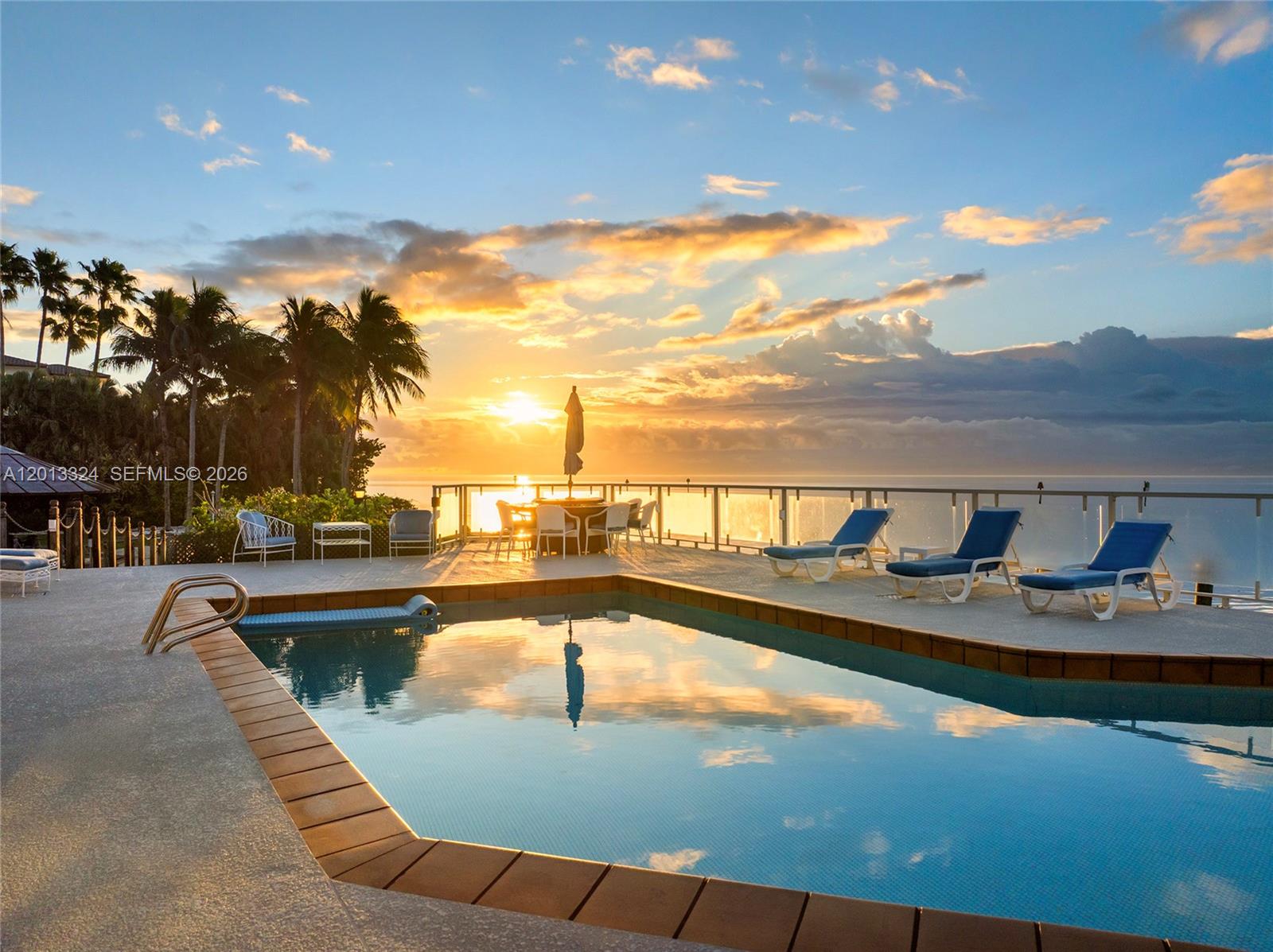 A waterfront patio features a swimming pool, lounge chairs, a boat lift, and palm trees — 720 Lugo Ave, Coral Gables FL 33156, CORAL GABLES, FL