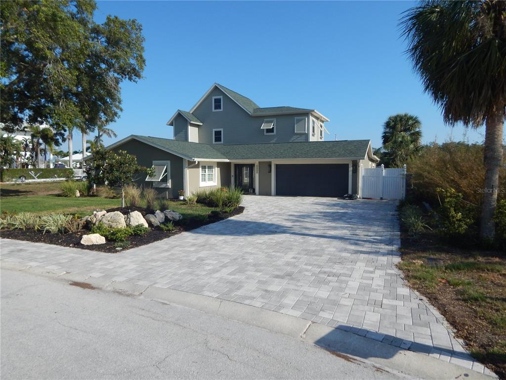 A two-story house with a gray exterior, green roof, and a paved driveway — 8025 ISLAND DRIVE, PORT RICHEY, FL