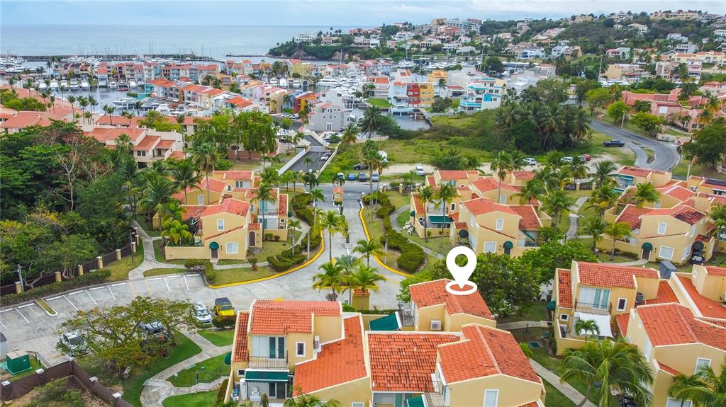 An aerial view shows a complex of tan townhouses with orange roofs near a marina — 215 HARBOUR DRIVE UNIT J1, HUMACAO, PR