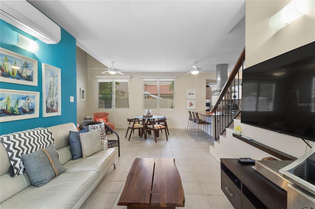 A living room and dining area with tile floors, a blue accent wall, and stairs — 215 HARBOUR DRIVE UNIT J1, HUMACAO, PR