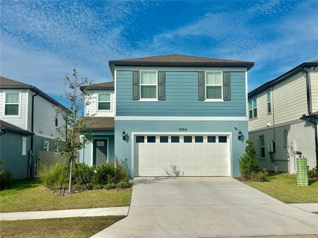 A two-story blue house with a white garage door and a concrete driveway — 1066 SILVERLAKE BOULEVARD, LAKE ALFRED, FL