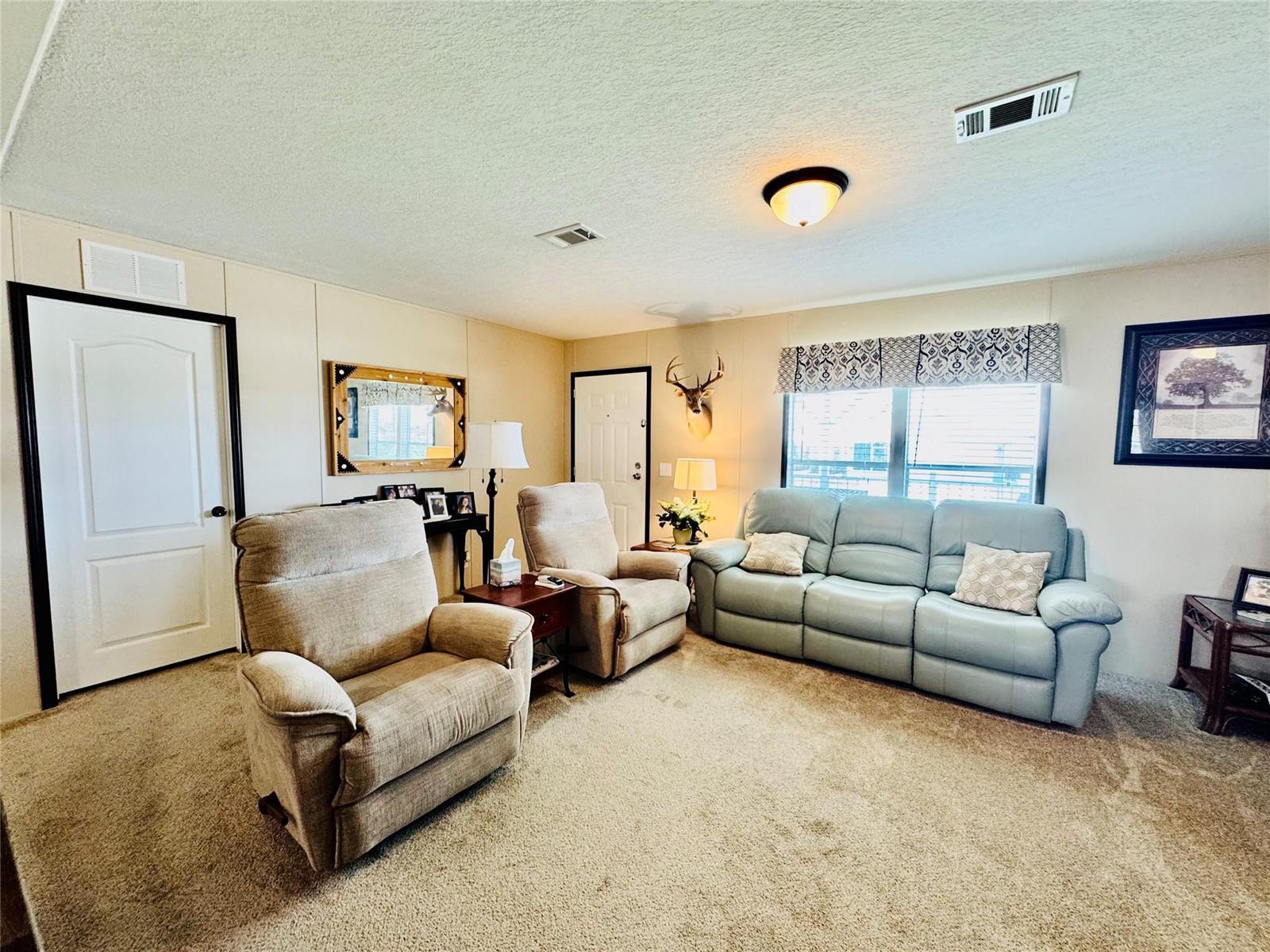 A living room features beige carpet, two recliners, and a light blue reclining sofa — 4350 SW 10th Avenue, Okeechobee FL 34974, OKEECHOBEE, FL