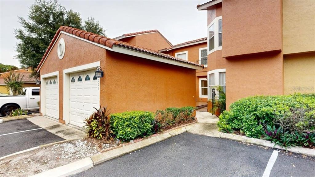 An exterior view of a two-story stucco building with a two-car garage and landscaping — 1009 CASA DEL SOL CIRCLE, ALTAMONTE SPRINGS, FL