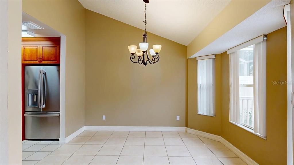 A dining area with tile floors, a chandelier, and a stainless steel refrigerator — 1009 CASA DEL SOL CIRCLE, ALTAMONTE SPRINGS, FL