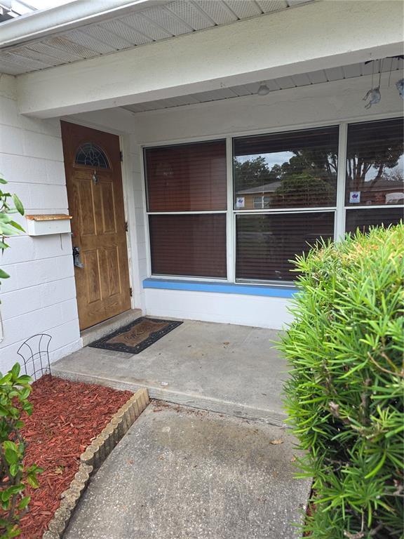 A front porch with a wooden door, large windows, and a small garden bed — 2444 37TH STREET N, ST PETERSBURG, FL