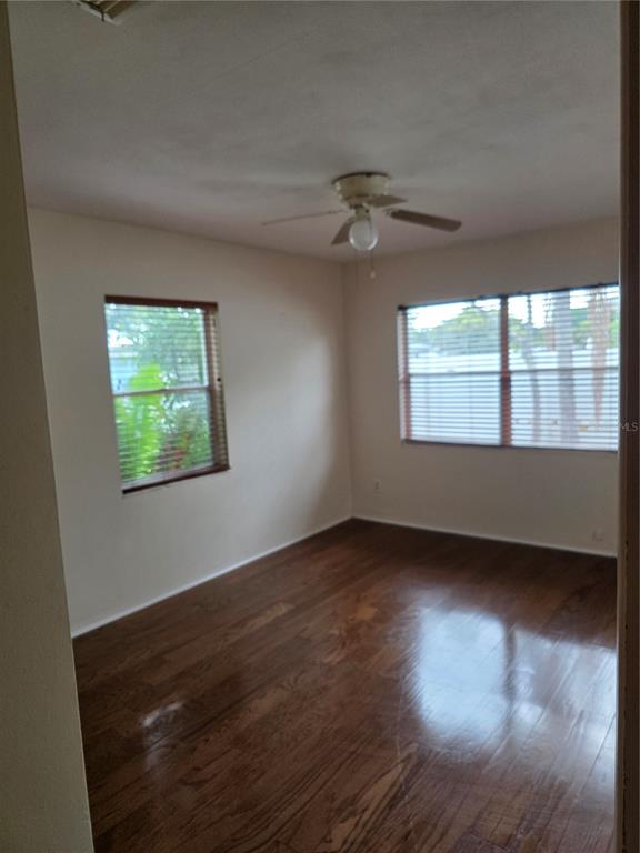 An empty bedroom with hardwood floors, two windows with blinds, and a ceiling fan — 2444 37TH STREET N, ST PETERSBURG, FL