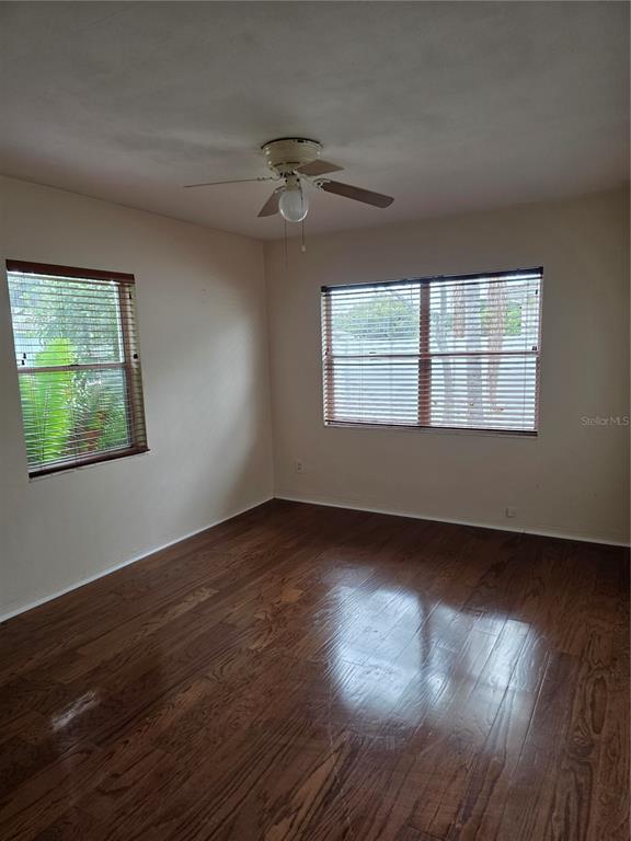 An empty bedroom features wood-look flooring, beige walls, a ceiling fan, and two windows — 2444 37TH STREET N, ST PETERSBURG, FL