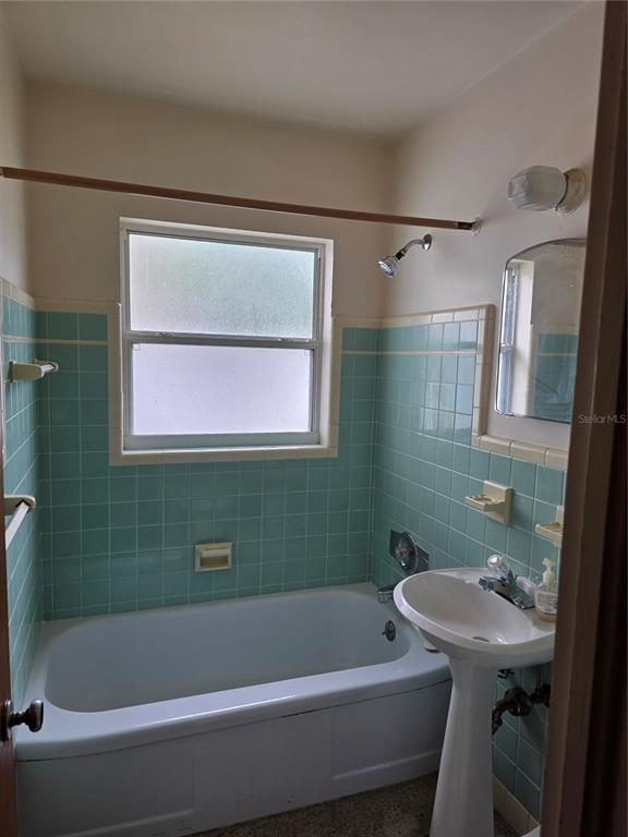 A bathroom features a white pedestal sink, a bathtub, and light blue wall tiles — 2444 37TH STREET N, ST PETERSBURG, FL